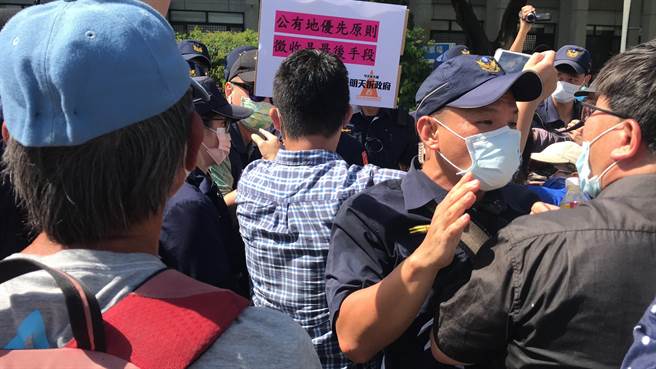 屏东火车站周边道路拓宽案波折不断，反迁民眾26日又到县府举布条还撒冥纸，期间与警方爆发激烈拉扯。（谢佳潾摄）