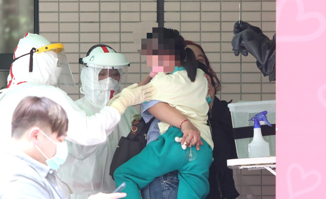 本土疫情升溫，家長帶著孩子去篩檢站篩檢。（本報系資料照）