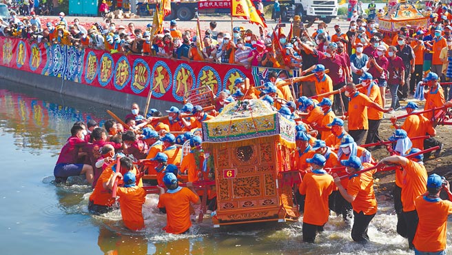 虽然今年规模缩小，嘉义县布袋镇新塭嘉应庙「衝水路、迎客王」祭典仍行礼如仪，吉时一到，在眾人吆喝声中，神轿陆续下水，绕行王船码头一圈后，将无形客王迎上岸。（吕妍庭摄）