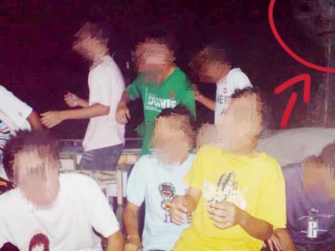 网友将照片调亮后，赫然发现右上角出现一张恐怖男性的苍白脸孔，正在怒视主角一群人。(图／灵异公社)