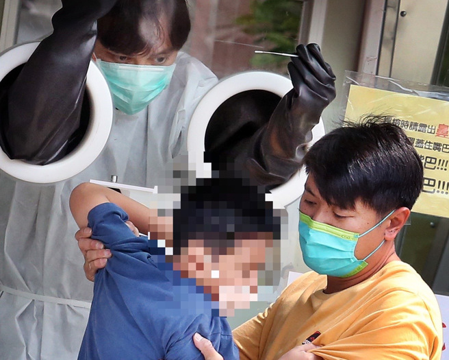 医院採检站1位害怕採检的学童试图挣脱，身旁的大人忙着安抚情绪。（范扬光摄）