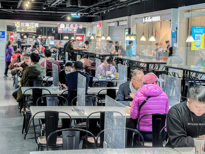 本土確診個案連日破萬例，是否禁止內用等議題再次掀起熱議。圖為民眾在美食街隔著板子用餐。（羅永銘攝）
