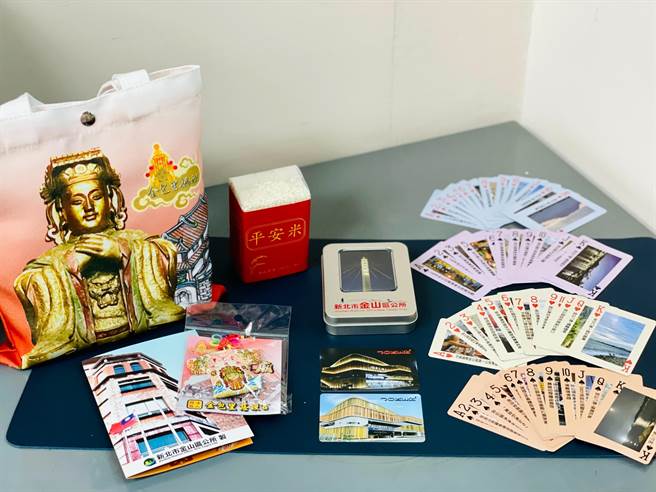 金山區公所響應金包里二媽回娘家活動所推出的平安福袋，內容有平安米1包、金山區特色圖片撲克牌含鐵盒1組、慈護宮小神衣吊飾及金山特色簡介卡片1張等。（金山區公所提供）