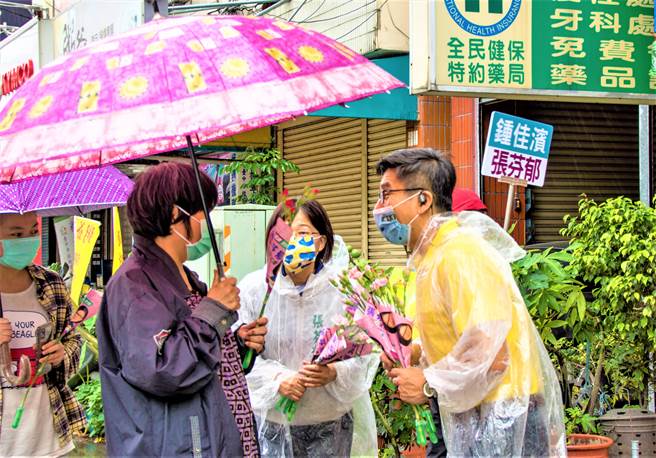 立委锺佳滨2日成为台中第13选区民进党初选超级助选员，在雨中与市议员参选人张芬郁分送康乃馨拉抬人气。（张芬郁服务处提供／卢金足台中传真）