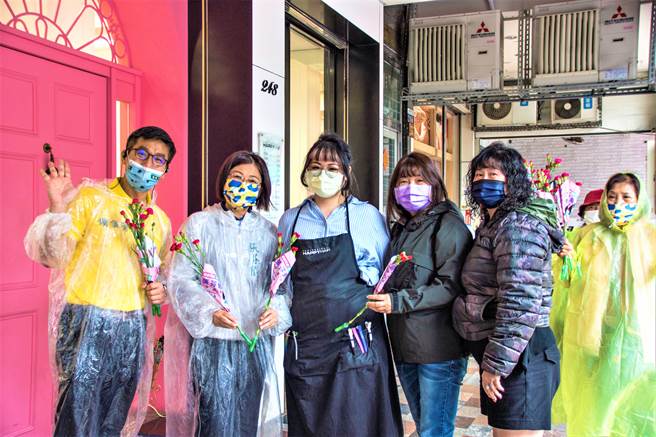 屏东立委锺佳滨（右起）2日冒雨与台中市议员参选人张芬郁沿街分送康乃馨给民眾。（张芬郁服务处提供／卢金足台中传真）