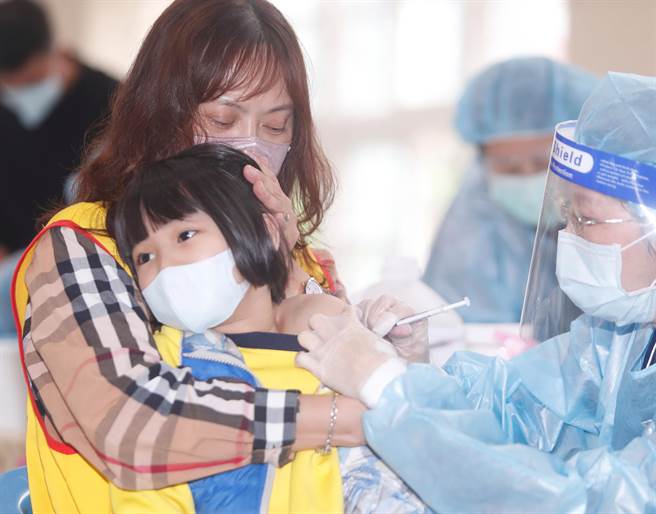 新冠肺炎疫苗日前開始為6-11歲學童接種，桃園市龜山區自強國小3日施打莫德納疫苗，一位高年級學童注射時緊靠志工的肩膀尋求安慰。(陳怡誠攝)