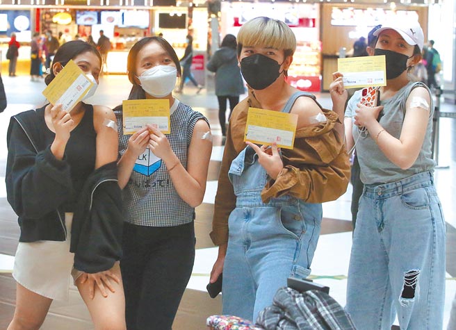 昨新增中重症21人，其中一名女性打完3劑仍重症。圖為在台北車站疫苗接種站有大批民眾與移工接種疫苗，完成後有人開心秀出疫苗接種紀錄卡拍照留念。（趙雙傑攝）