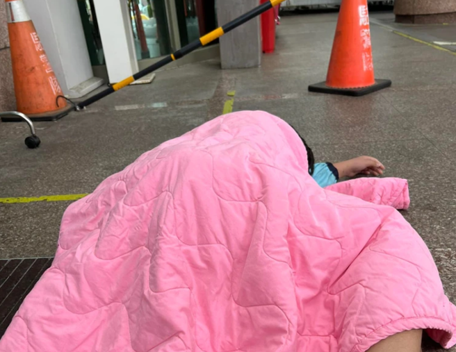 小孩疑似確診燒到39度，在急診室外癱軟躺地。（翻攝爆料公社）