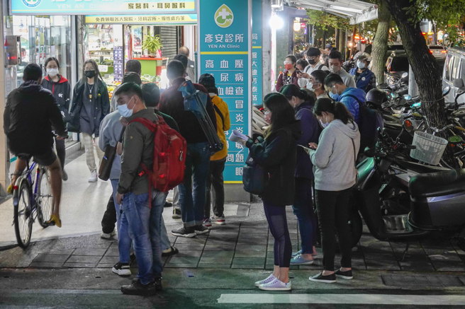 疫情不斷升溫，不少民眾下班後排隊買快篩試劑。（黃子明攝）