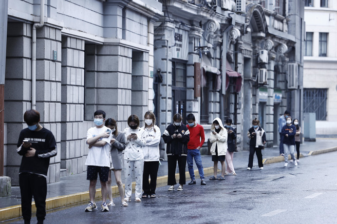 受疫情封控措施影響 ，大陸4月服務業製造業PMI連2個月創新低，經濟景氣持續下滑。圖為上海市民排隊做核酸檢測。（圖／中新社）