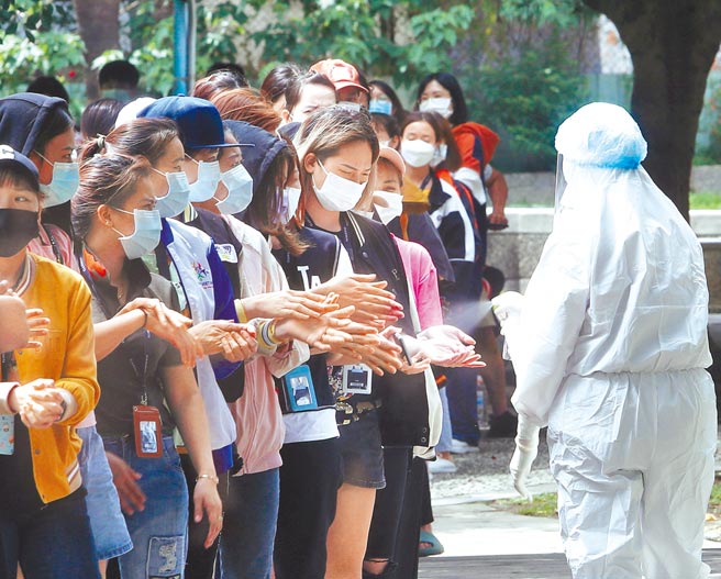 新冠疫情爆发，4日中重症患者再创新高，各地筛检站排队人潮恐造成另波群聚传染，护理人员特地为等候民眾消毒。（陈怡诚摄）