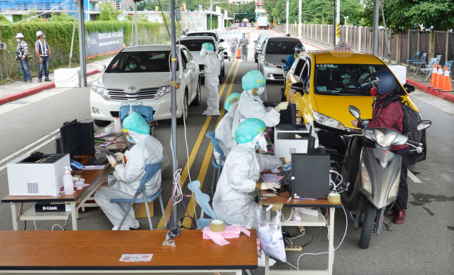 民眾駕車或騎車前往車來速篩檢站接受採檢，醫護人員則包裹著全套防護裝為民眾服務。（姚志平攝）