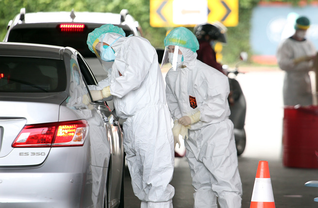 本土確診爆不停，醫護人員穿全套防護裝為民眾篩檢。（姚志平攝）