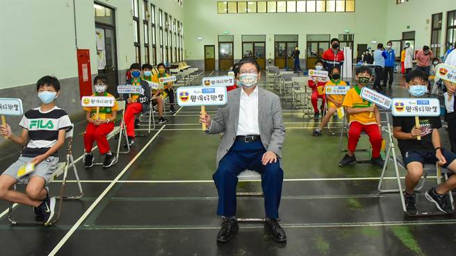 縣長楊文科（中）到新社國小了解學生接種情形，在觀察區與接種完疫苗的學童一起拿「覺得好興奮」的牌子，提振精神。（羅浚濱攝）