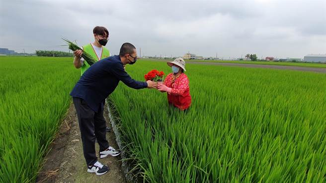 在西螺镇开咖啡车的年轻人赖柏村（前），专程帮阿仁送一束康乃馨和一杯咖啡给在田里工作的阿仁妈妈（右）。（创世基金会提供）