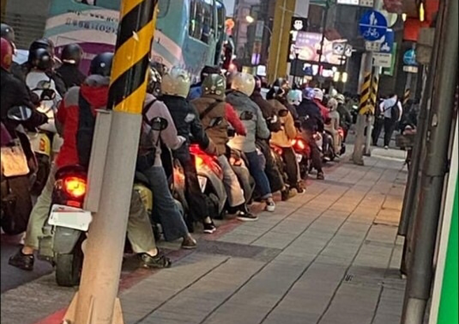 整排机车骑士等红灯时「有默契」地伸右脚放在人行道的水泥砖上，乍看变成「人形蜈蚣」，不少网友笑说这个姿势真的很舒服，纷纷喊说「我也会」。（翻摄自脸书「靠北景点2.0」）
