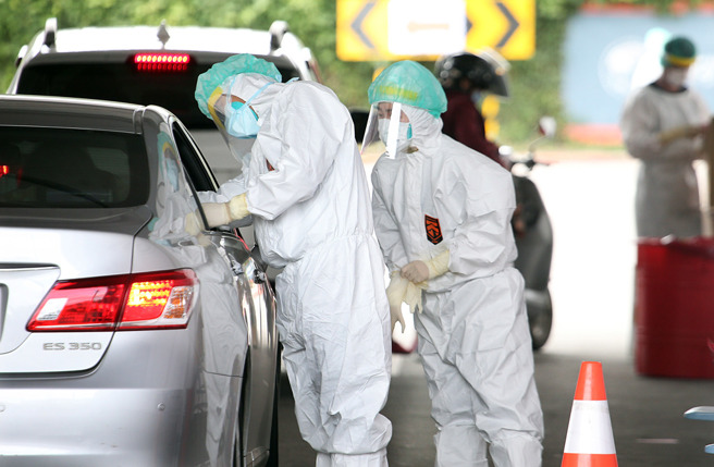 图为北市「快筛得来速」，医护全副武装帮驱车前来的民眾筛检。（资料照／姚志平摄）
