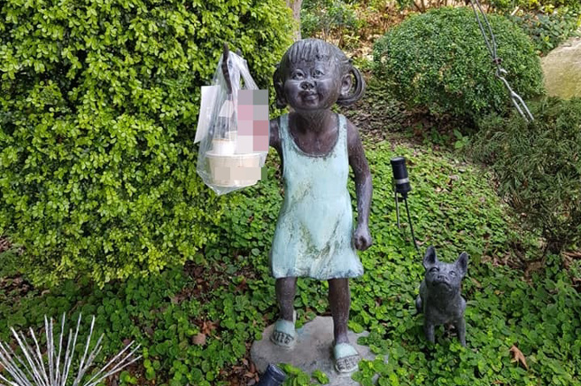 午餐遭外送員掛在小女孩銅像手中。（圖／翻攝自爆廢公社）