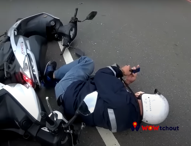 新竹县宝山乡3日发生一起车祸，一名阿伯骑士被撞后，维持原姿势侧躺在地上滑手机。（翻摄自YouTube频道「WoWtchout - 地图型行车影像分享平台」）