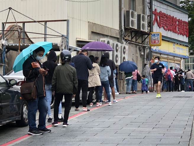 金門出現單日最多確診個案，累計208例。圖為民眾今天中午冒雨排隊購買快篩劑。（李金生攝）