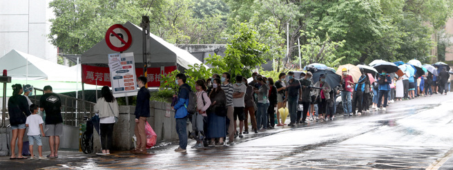 新冠肺炎疫情日渐严峻，本土每日确诊人数已突破5万人，北市万芳医院的Covid-19社区筛检站11日一早就有大批民眾冒雨排队进行採检，以厘清是否确诊新冠肺炎的疑虑。（郑任南摄）