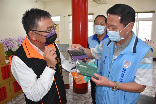 陈国宾（左）向后龙镇长朱秋隆简介自家口罩优点。（谢明俊摄）