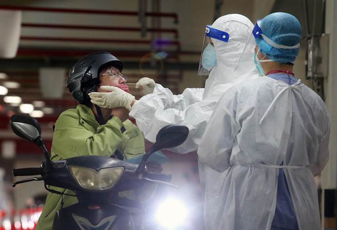 捷運木柵機廠停車場增設的「防疫急門診」11日起開始營運，預計每日可以為800名快篩陽性民眾PCR採檢。在停車場內，醫護人員正在為1名機車騎士採檢。（范揚光攝）