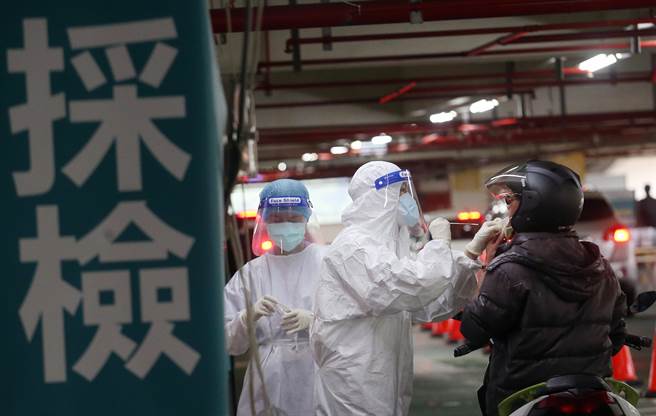 捷運木柵機廠停車場增設的「防疫急門診」11日起開始營運，預計每日可以為800名快篩陽性民眾PCR採檢。在停車場內，醫護人員正在為1名機車騎士採檢。（范揚光攝）