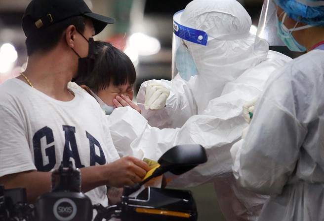 捷運木柵機廠停車場增設的「防疫急門診」11日起開始營運，預計每日可以為800名快篩陽性民眾PCR採檢。一位學童受不了採檢的不適，忍不住用手按住鼻子。（范揚光攝）