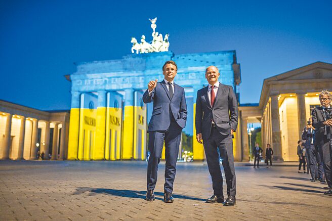 法国总统马克宏（左）和德国总理萧兹在打上乌克兰国旗、蓝黄两色灯光的布兰登堡门，展现对乌克兰的支持。（美联社）