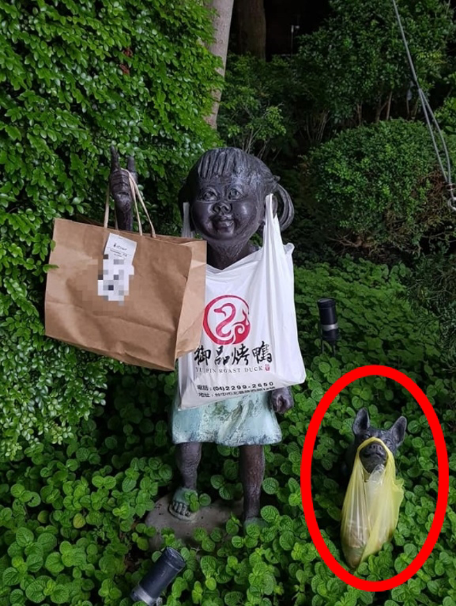 外送員把餐掛在小女孩雕像手上，沒想到外送員創意進化，小女孩不但手上掛餐，耳朵也掛餐，就連一旁小狗雕像，狗嘴也掛餐。（翻攝自臉書臉書「爆廢公社」）