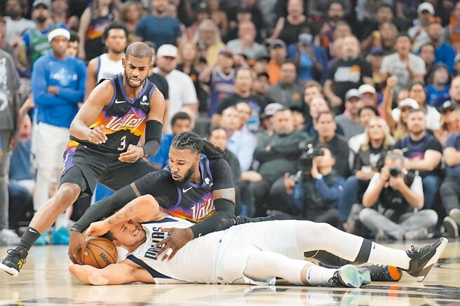 太陽克勞德（右）試圖從倒地的獨行俠東契奇（下）手中搶球，控衛保羅也在一旁伺機下手。（路透）