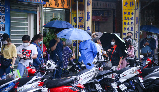 唾液快篩開賣，圖為許多民眾冒雨排隊購買。（資料照/羅永銘攝）