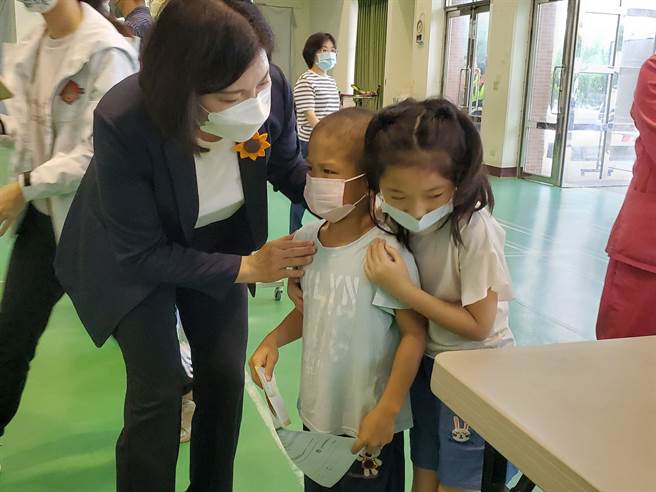 斗南镇大东国小一名小一男孩怕打针，同校女同学（右一）和县长张丽善（左）一起安慰他。（周丽兰摄）