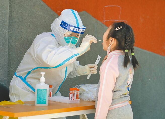 5月13日，在北京市海澱區八里莊街道首師大社區的一處臨時核酸檢測採樣點，醫護人員進行核酸採樣。（新華社）