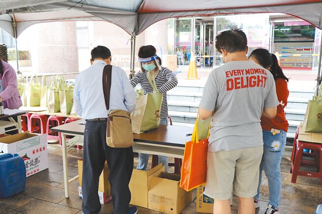 桃园市中坜区公所工作人员与代领民眾确认资料与防疫包内容物。（蔡明亘摄）