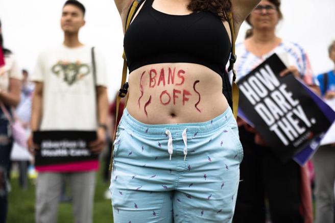  美国一名示威女子肚皮上写着「禁令滚开」的标语，反对最高法院推翻保障妇女堕胎权的「罗诉韦德案」歷史性裁决案。（图/ 中央社）