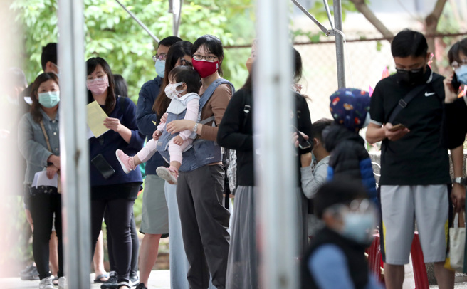 图为民眾带着小朋友在北市妇幼院区排队，等候筛检看诊。（郑任南摄）