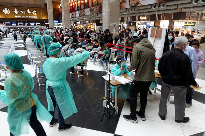 新冠肺炎本土疫情持續嚴峻，連日來確診病例數突破6萬，圖為台北車站大廳疫苗接種站15日湧入數百人排隊施打，醫護人員在人龍間穿梭。（黃世麒攝）