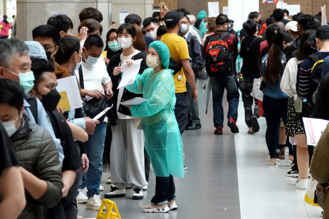 台北车站大厅的疫苗接种站15日涌入数百人排队施打，医护人员在人龙间穿梭。（黄世麒摄）
