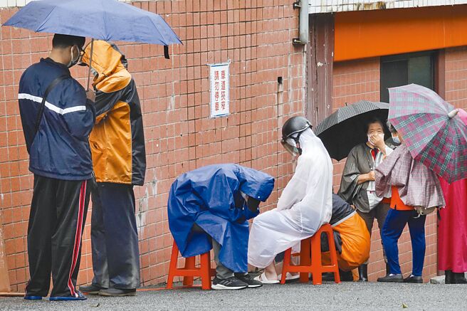 台北市松山慈惠堂14、15日連續兩天發放免費快篩試劑，大批市民一早撐傘穿雨衣在細雨中排隊領取。（黃子明攝）