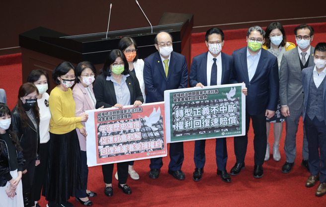 立法院17日院会三读通过「威权统治时期国家不法行为被害者权利回復条例草案」，民进党立委在议场中央举着「转型正义不中断，权利回復速赔偿」及「平復歷史伤痕、促进社会和解，回復被害者受损权利」标语合影留念。（姚志平摄）