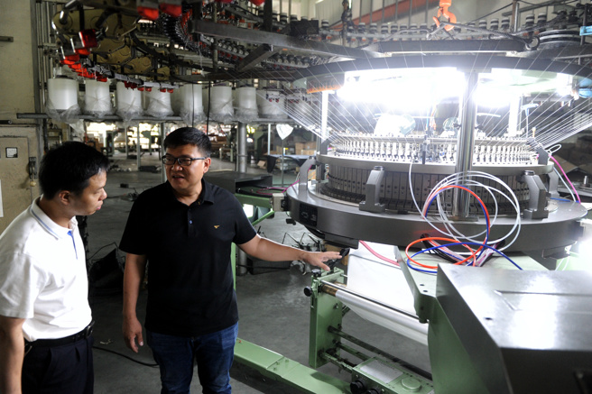 陈胜裕（右）向参访者介绍针织大圆机生产情况。（作者提供）