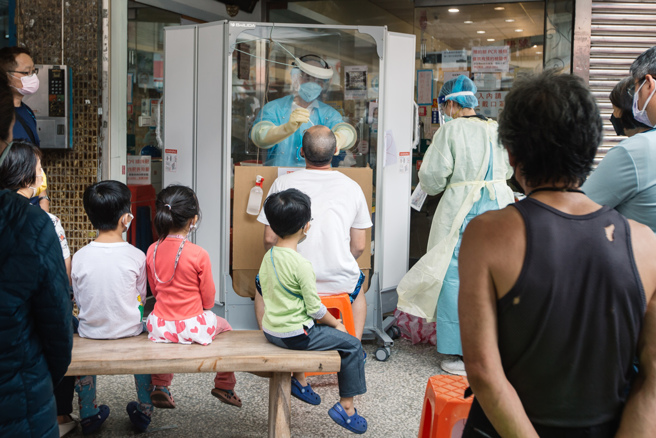 居家照护改赔慰问金，寿险公会仅讨论没做出结论。本土疫情持续延烧，家长带着小朋友去採检。（郭吉铨摄）

