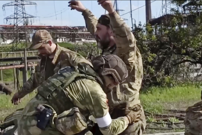 烏克蘭部隊5月17日撤出馬立波（Mariupol）亞速鋼鐵廠後，俄軍趨前搜身的畫面。（俄羅斯國防部）