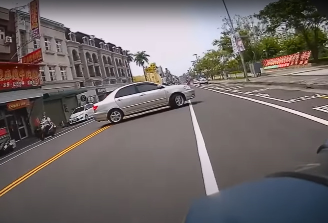 有輛轎車跨雙黃線違規迴轉差點撞上重機，後來而來的機車騎士差點撞上大罵「三字經」。（翻攝自YouTube頻道「WoWtchout - 地圖型行車影像分享平台」）