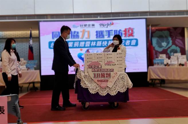 台塑公司捐贈自產的快篩劑10萬劑給雲林縣府，19日舉行捐贈儀式，台塑麥寮管理部協理蔡建樑（左二）推著疊滿快篩劑的小車子，右為雲林縣長張麗善。（周麗蘭攝）
