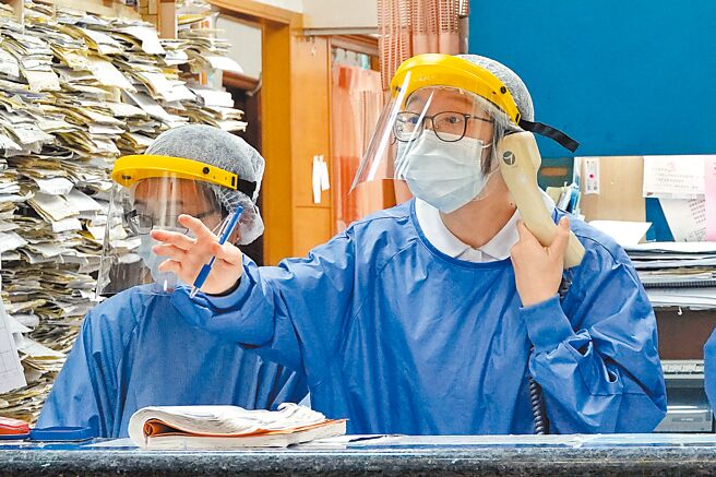 新莊一間基層診所，工作人員身穿全套防護裝備，一邊接電話處理預約事宜，一邊應付現場候診的民眾。（黃世麒攝）