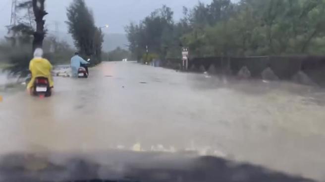 受到南方雲系影響，恆春20日清晨5時下起大雨，3小時雨量就已突破200毫米，導致道路積水無法通行，水淹半個輪胎高，無奈騎士只能牽車度過泥流馬路。（圖/ 中央社）