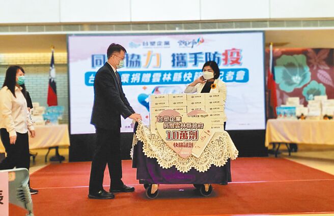 台塑公司捐赠10万剂快筛剂给云林县政府，19日捐赠仪式中，台塑麦寮管理部协理蔡建梁（左二）推着迭满快筛剂的小车子，右为云林县长张丽善。（周丽兰摄）